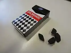 Une boîte et des bonbons au salmiak sur une table.