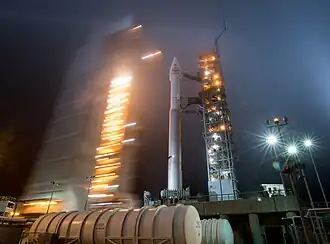 Photo prise de nuit du lanceur spatial Atlas V avec la tour de service sur son pas de tir.