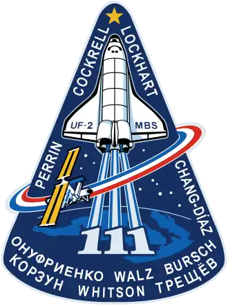 Le logo de la mission STS-111 de la navette spatiale Endeavour vers la Station spatiale internationale en 2002.Les trois « 1 » signifiant le numéro de la mission, de par leur forme verticale, se confondent avec la représentation stylisée des flammes blanches de la navette.