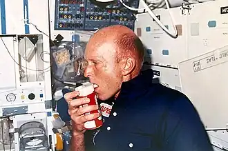 Gordon Fullerton, commandant de la mission STS-51F, avec une canette de Coca-Cola