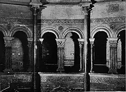 Photographie en noir et blanc montrant une galerie à six arcades.