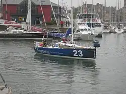 Voilier bleu s'éloignant du quai au moteur.