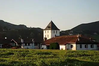 Photographie du clocher-tour d'une église au-dessus des maisons d'un village.