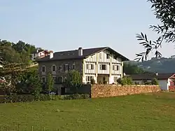 vue de trois quarts d'une maison à deux étages aux pans de bois vert.