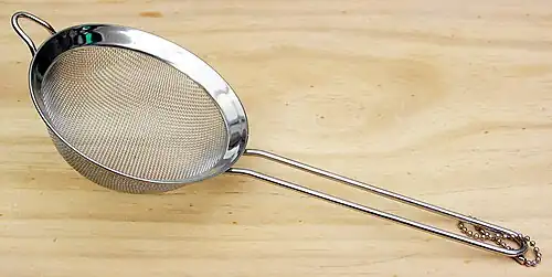 Passoire métallique dotée d'un long manche