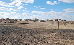 Photographie d'un paysage désertique, en arrière-plan duquel se trouve une ville.