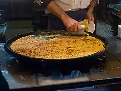 Grande et fine galette cuite de couleur jaune orangée au sortir du four en train d'être servie sur sa plaque.