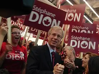 Photographie de Stéphane Dion, entouré de militants brandissant des pancartes rouges portant son nom, au congrès d'investiture du Parti libéral du Canada de 2006