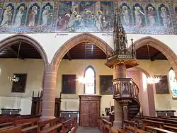 Chaire à prêcher du XIXe&nbsp;siècle, fresques néo-gothiques "Saints et Adoration des Rois mages" (XXe&nbsp;siècle) et collatéral.