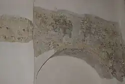 Arc en pierre replâtré de frais au-dessus duquel on aperçoit des traces de peinture ancienne.