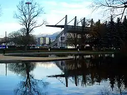 Un plan d'eau au premier plan devant une tribune de stade et des arbres