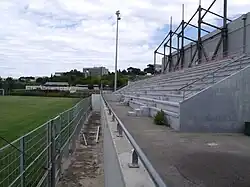Tribune du stade à droite de la pelouse du stade.