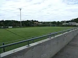 Vue du stade depuis la tribune, sous un ciel nuageux.