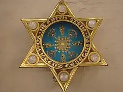 Photographie d'une parure vestimentaire formée d'une étoile de David dorée