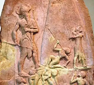 Détail d'un bas-relief représentant un homme victorieux, doté d'un casque à cornes, dominant de plus petits personnages.