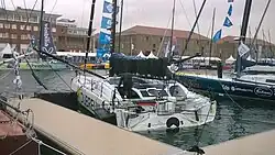 Vu de trois quarts arrière, foiler blanc amarré au ponton.