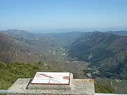 Panorama depuis la grande table d’orientation à 300&nbsp;m du sommet sur la route depuis Valgorge et sur le Cham du Cros (1&nbsp;202&nbsp;m) à gauche.