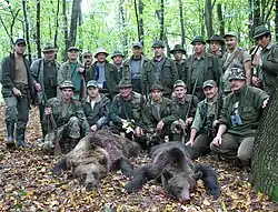 Un groupe de chasseurs posent devant deux ours morts.