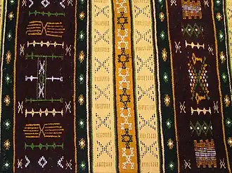 Un tapis kabyle multicolore avec des motifs géométriques.
