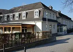 Photo d'une batiment blanc avec un toit gris donnant sur une allée pavée.