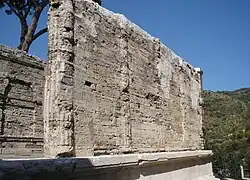 Photographie en couleurs des murs ruinés d'un édifice à colonnes.