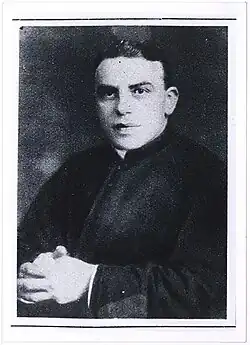 Photo noir et blanc d'une personne assise, mains croisées.