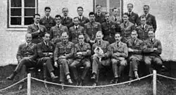 Photographie (noir et blanc) de classe. Les étudiants sont sur 3 rangs.