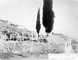 Photographie ancienne en noir et blanc d'un cimetière méditerranéen à flanc de colline.