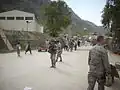 Les 82e soldats et les unités logistiques de la Force opérationnelle interarmées combinées marchent dans la zone frontalière de Torkham avec le directeur du Centre d'opérations de déploiement et de distribution du CENTCOM, major général de l'armée de l'air américaine, Robert McMahon, le 25 mars 2010 à Torkham, en Afghanistan.