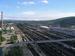 la photo montre une grande succession de voies ferrées vues depuis un point haut et traversée par une passerelle.