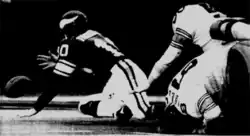 Image en noir et blanc d'un joueur à genou cherchant à récupérer un ballon perdu