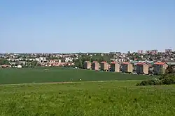 Alignement de petits immeubles collectifs en bordure d'une zone agricole en légère cuvette.