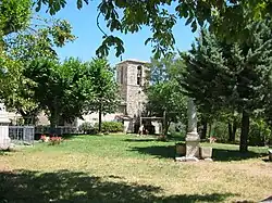 Pelouse bordée d’arbres, mère poussant sa fille sur une balançoire, et clocher carré massif