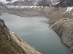 Vue générale du lac du Chevril vide avec les restes de l'ancien village de Tignes au fond.