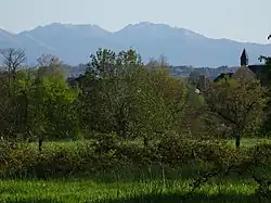 Photographie en couleurs d'une église et de montagnes au fond.