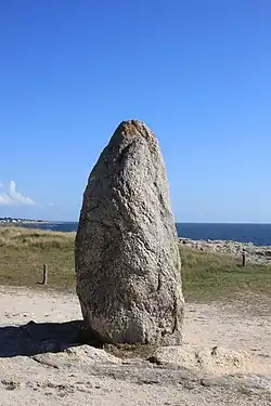 Vue d’un menhir sur fond de ciel bleu.