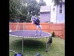Deux personnes sur un trampoline effectuant une souplesse.