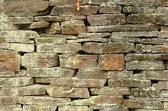 Parement de mur en pierres plates posées dans le sens du lit de carrière et avec croisement des joints (lieu non précisé).