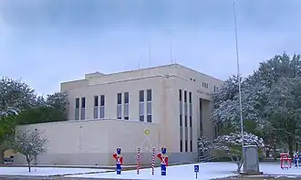 Vue d'un bâtiment de plusieurs étages. De la neige est présente sur les trottoirs.