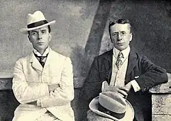 Deux hommes en costume, l'un blanc, l'autre sombre. Ressemblance de famille.