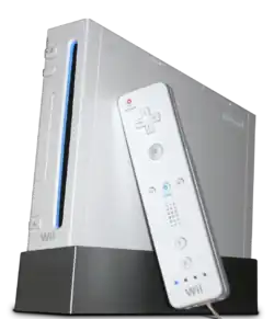 Une console de jeux vidéo Wii, dressée à la verticale sur un socle. Une Wiimote, contrôleur de jeu semblable à une télécommande, est posée contre la console.