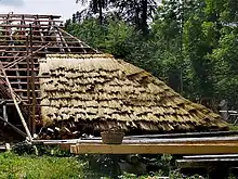 Couverture d’un toit de chaume de paille, partiellement terminée.