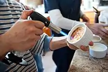 Photo d’une crème brûlée entrain d’être caramélisée.