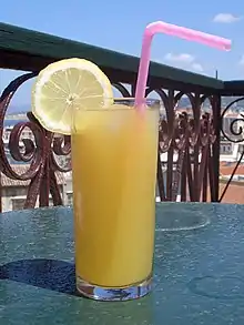 Une Boisson dans un verre, avec une lame de citron et une paille.