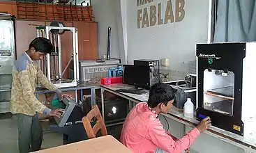 Deux hommes, l'un assis et l'autre debout, règlent des appareils.