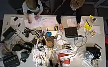 Photographie de deux personnes avec des ordinateurs et des machines.