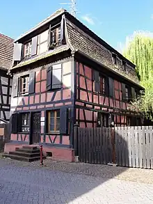 Photographie d'un bâtiment à colombage et enduit rose.