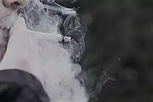 Photo de fumée de cigarette expulsée du visage d’une personne.