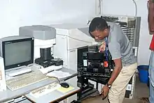 Photographie d'un homme entouré d'appareils électroniques.