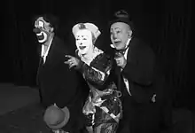 Photographie en noir et blanc de trois hommes aux visages peints.